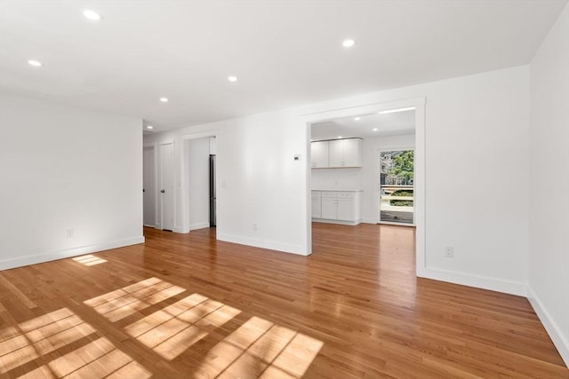 unfurnished living room featuring recessed lighting, light wood-style flooring, and baseboards