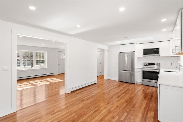 kitchen featuring appliances with stainless steel finishes, a baseboard radiator, light countertops, and a sink