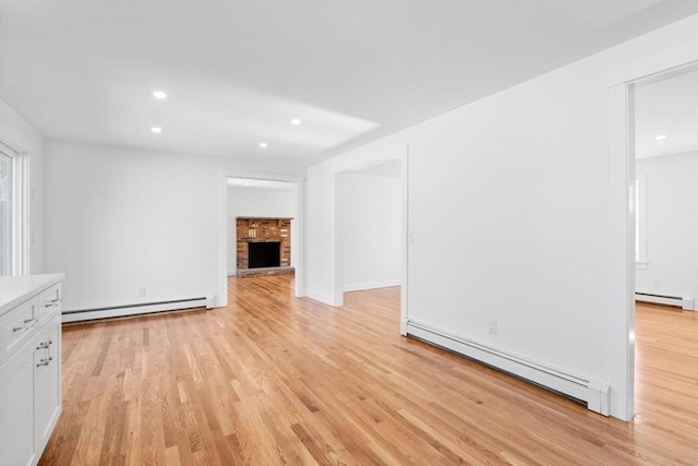 unfurnished living room featuring a baseboard heating unit, a fireplace, and light wood-style flooring