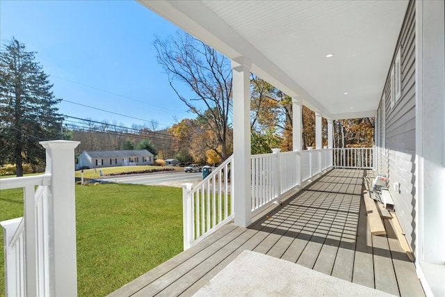 wooden deck featuring covered porch and a lawn