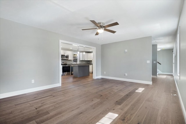 unfurnished living room featuring ceiling fan and hardwood / wood-style floors