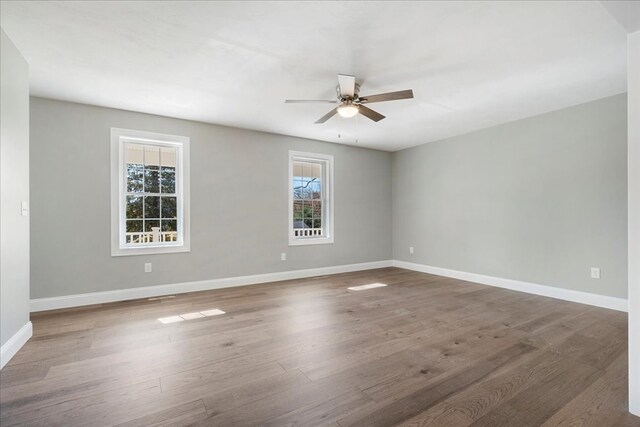 unfurnished room with dark wood-type flooring, a healthy amount of sunlight, and ceiling fan