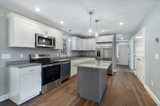 kitchen with a kitchen island, white cabinetry, sink, decorative light fixtures, and stainless steel appliances