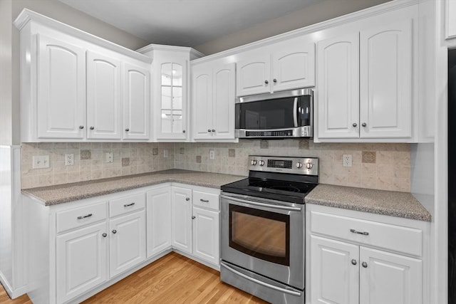 kitchen featuring stainless steel appliances, white cabinets, light wood-style floors, and light countertops