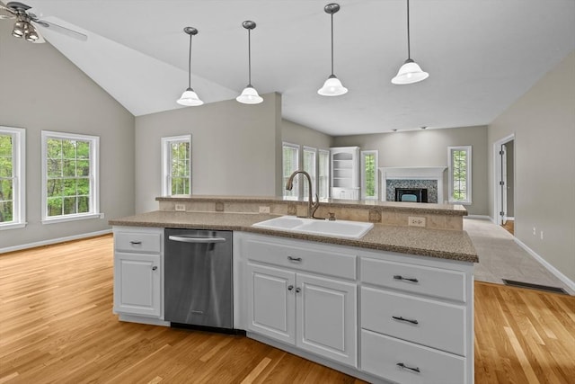kitchen with dishwasher, a sink, open floor plan, light wood-type flooring, and lofted ceiling