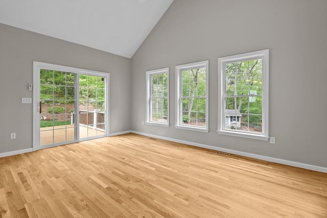 unfurnished room featuring light wood finished floors, baseboards, and high vaulted ceiling