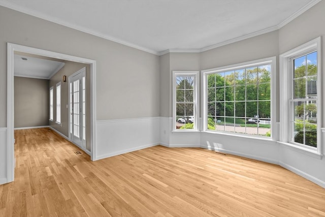 unfurnished room featuring light wood finished floors, crown molding, and baseboards