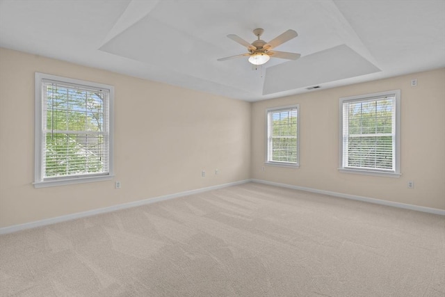 unfurnished room featuring a raised ceiling, plenty of natural light, and baseboards