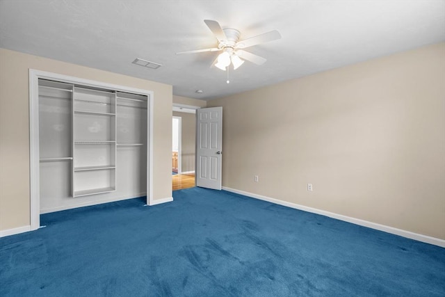 unfurnished bedroom with dark colored carpet, a closet, baseboards, and ceiling fan