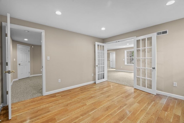 empty room featuring french doors, recessed lighting, baseboards, and light wood-style flooring