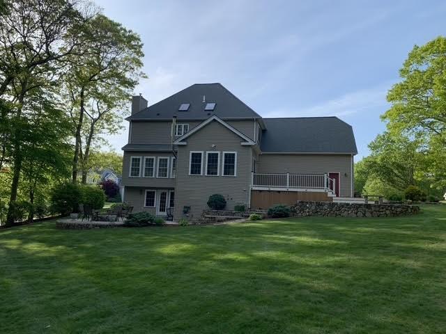rear view of house featuring a chimney and a lawn