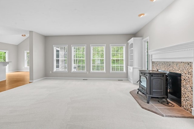 unfurnished living room featuring a wood stove, carpet, and baseboards