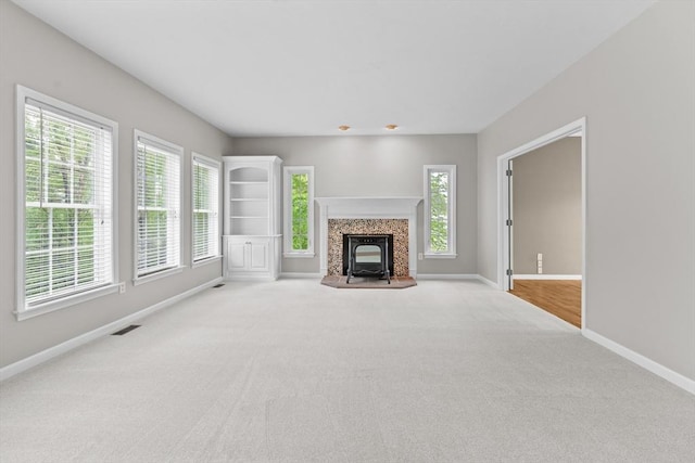 unfurnished living room featuring baseboards, carpet floors, and plenty of natural light
