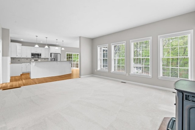 unfurnished living room featuring light carpet, baseboards, and recessed lighting