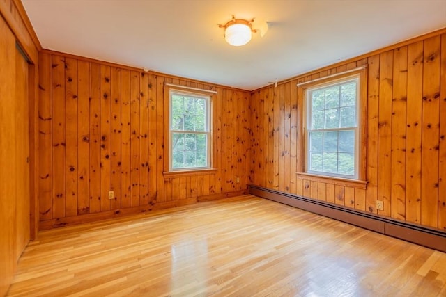 22 Liberty St, Bellingham, MA 02019 - spare room featuring a baseboard heating unit, healthy amount of natural light, light wood-type flooring, and wooden walls