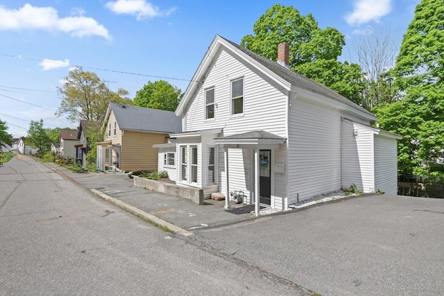 10 Jackson St, Ayer, MA 01432 - view of front of property with roof with shingles, uncovered parking, and a chimney