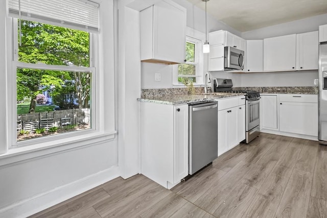 10 Jackson St, Ayer, MA 01432 - kitchen featuring stainless steel appliances, light stone countertops, light wood-type flooring, white cabinetry, and a sink