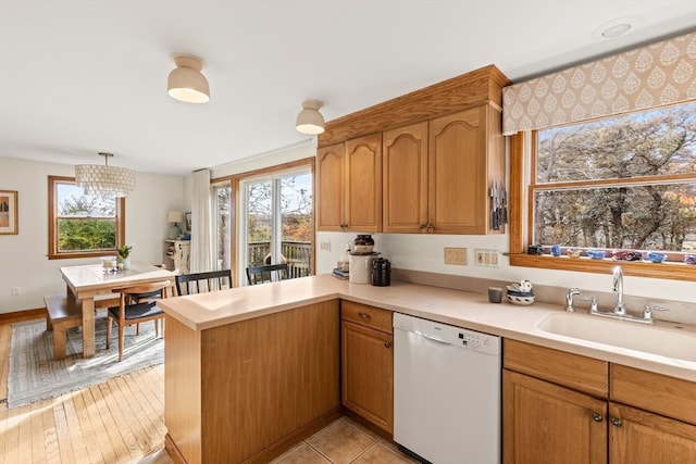 kitchen with kitchen peninsula, sink, white dishwasher, and plenty of natural light