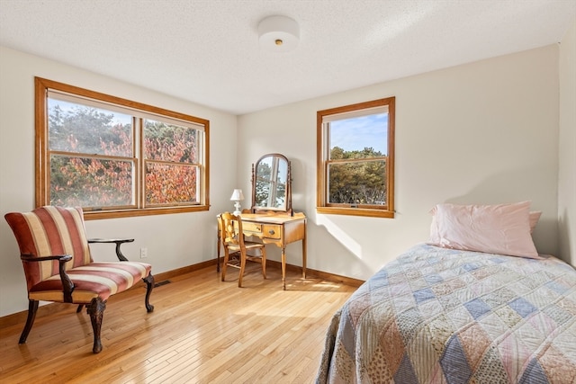 bedroom with a textured ceiling and light wood-type flooring