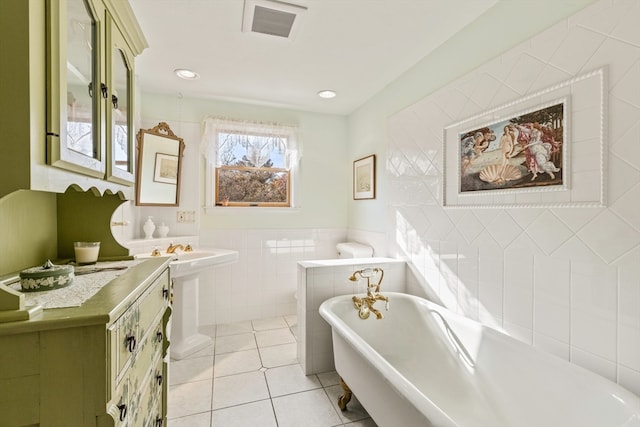 bathroom featuring a bathing tub, tile patterned flooring, and tile walls