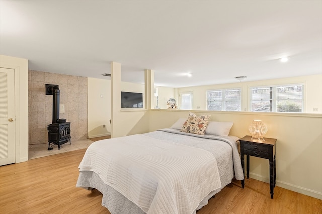 bedroom with hardwood / wood-style floors and a wood stove