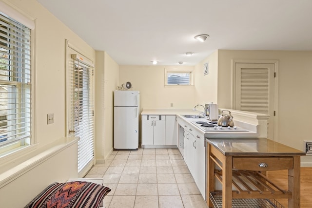 kitchen with white cabinetry, sink, white appliances, and light tile patterned floors