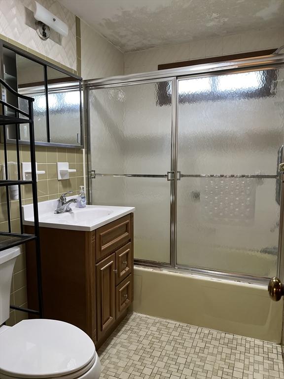 50 Feltham Rd, Springfield, MA 01118 - bathroom featuring toilet, vanity, enclosed tub / shower combo, and tile walls