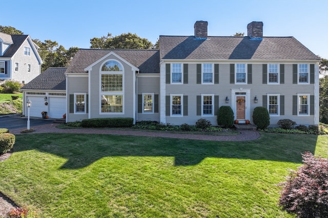 colonial inspired home featuring a front lawn and a garage