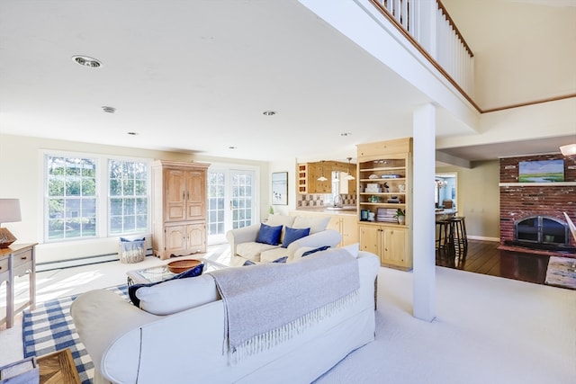 living room with a fireplace, baseboard heating, and light wood-type flooring