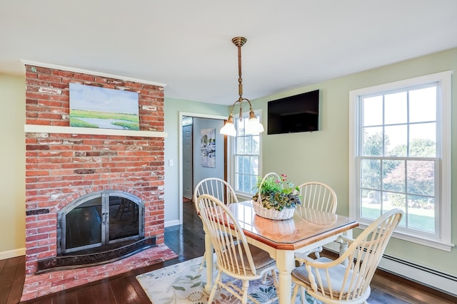 dining room with a brick fireplace, a notable chandelier, baseboard heating, and dark wood-type flooring