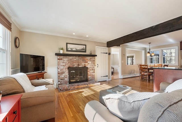 16 Kirsi Cir, Westford, MA 01886 - living area featuring a baseboard radiator, hardwood / wood-style flooring, a brick fireplace, crown molding, and a chandelier