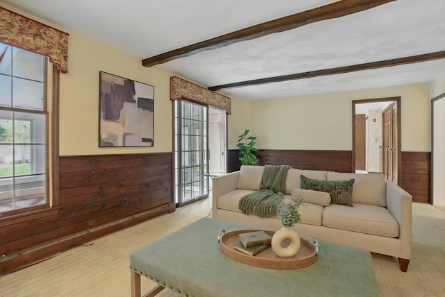 living area with a wainscoted wall, wooden walls, and beamed ceiling