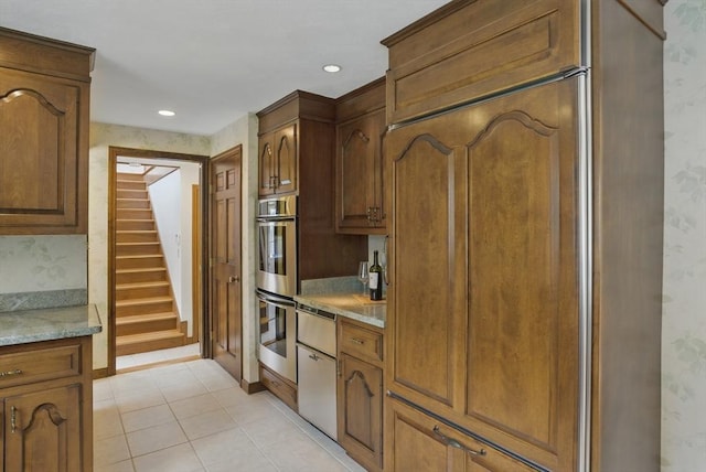 kitchen with dishwasher, double oven, wallpapered walls, light countertops, and light tile patterned floors