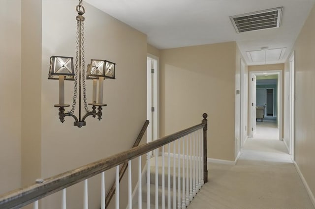 hall with visible vents, light carpet, baseboards, attic access, and an upstairs landing