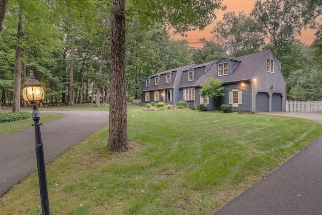view of front of property featuring fence, roof with shingles, aphalt driveway, a garage, and a lawn