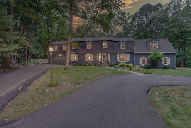view of front of property with a garage, aphalt driveway, and a yard