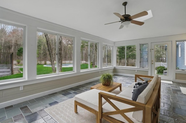sunroom / solarium featuring baseboards, vaulted ceiling, and stone tile flooring