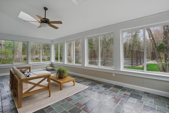 sunroom with stone tile floors and vaulted ceiling with skylight
