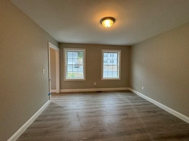 unfurnished room featuring baseboards and dark wood finished floors