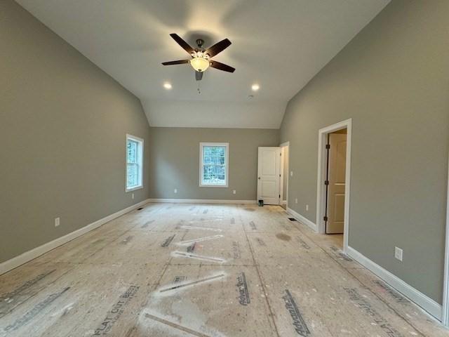 unfurnished bedroom featuring vaulted ceiling, a ceiling fan, and baseboards