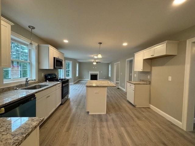 kitchen featuring a kitchen island, stainless steel appliances, white cabinetry, pendant lighting, and a sink