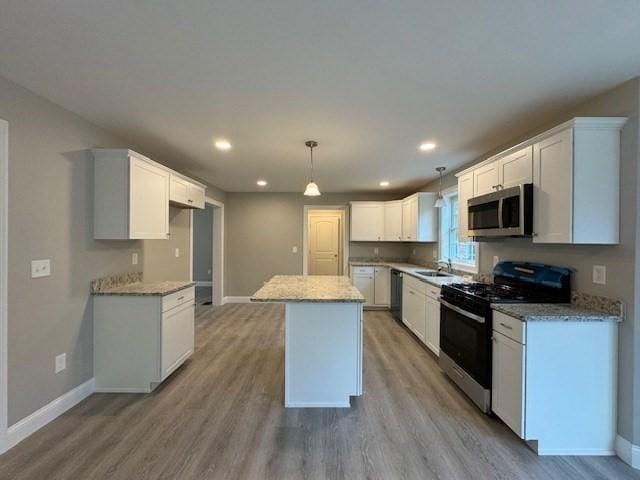 kitchen with light wood-style flooring, white cabinetry, appliances with stainless steel finishes, a center island, and pendant lighting