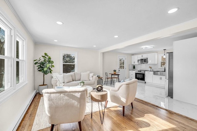 living area with baseboards, baseboard heating, crown molding, light wood-type flooring, and recessed lighting