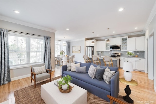 living area featuring recessed lighting, baseboards, light wood-type flooring, and ornamental molding