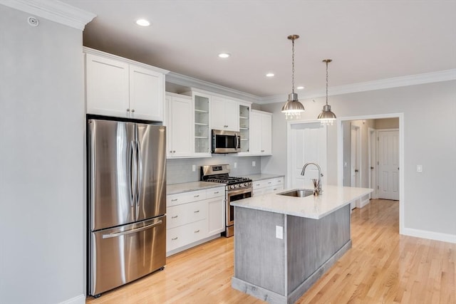 kitchen with light wood finished floors, ornamental molding, appliances with stainless steel finishes, and a sink