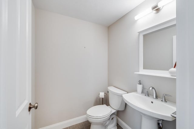 half bath with a sink, baseboards, and toilet