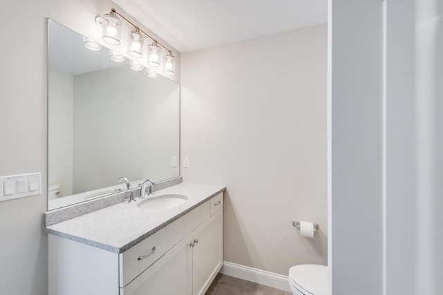 bathroom with vanity, toilet, and baseboards