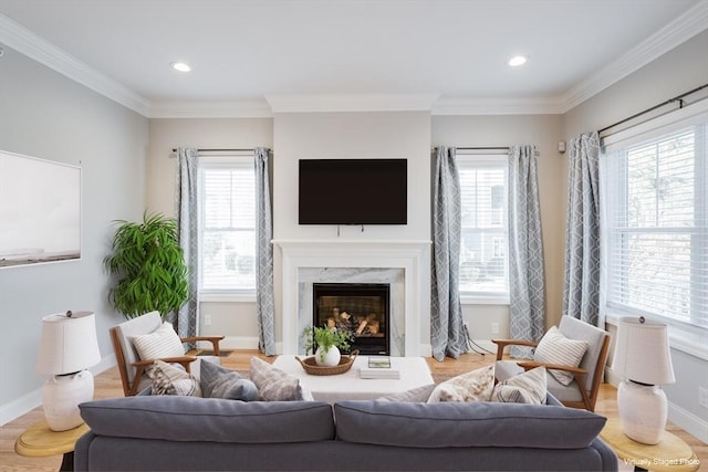 living room with a wealth of natural light, light wood-type flooring, a high end fireplace, and ornamental molding