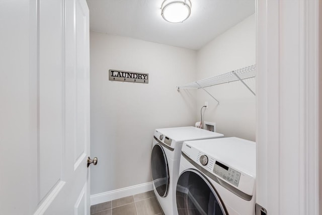 washroom featuring baseboards, separate washer and dryer, light tile patterned flooring, and laundry area