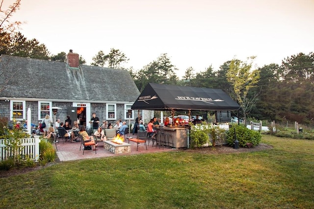 rear view of house featuring a patio area, a lawn, a fire pit, and fence